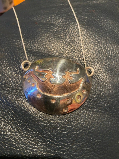 Boat People Pictograph Necklace displayed on black foam sheet